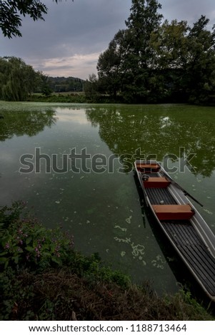 Narrow small boat at the bank of the river in summer at sunset
