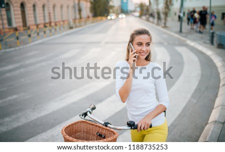 Girl with a bike talking on the phone in the city.