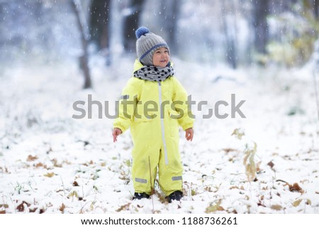 full length shot of happy boy in yellow snowsuit standing in snowy park Royalty-Free Stock Photo #1188736261