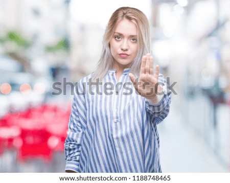Young blonde woman over isolated background doing stop sing with palm of the hand. Warning expression with negative and serious gesture on the face.