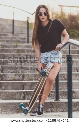 Beautiful young woman posing with a skateboard