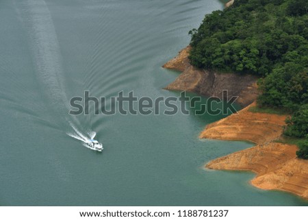 The ship crossed the lake and caused a ripple, and the khaki-coloured island was shaped like a jagged one.