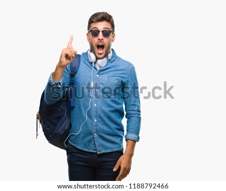 Young handsome tourist man wearing headphones and backpack over isolated background pointing finger up with successful idea. Exited and happy. Number one.
