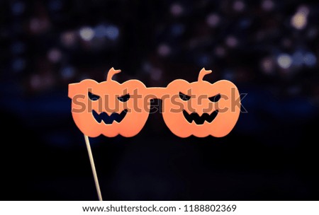 Showing scary pumpkin paper glasses on stick and background with purple bokeh. Concept of fancy Halloween party , holiday and celebrities .