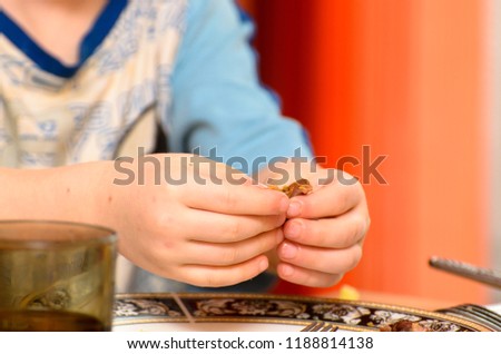 Picture of a boy's hand holding meat from dinner