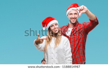 Young couple in love wearing christmas hat over isolated background smiling making frame with hands and fingers with happy face. Creativity and photography concept.