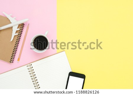 Flat lay design of travel summer concept - Top view of blank paper notebook, mock up smartphone, airplane, coffee cup and plane on pink yellow pastel color. Travel summer on pastel color background.