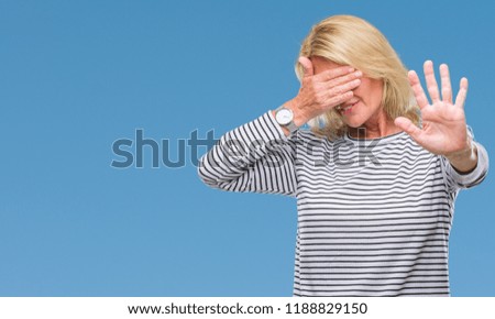 Middle age blonde woman over isolated background covering eyes with hands and doing stop gesture with sad and fear expression. Embarrassed and negative concept.