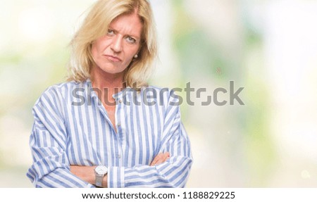Middle age blonde business woman over isolated background skeptic and nervous, disapproving expression on face with crossed arms. Negative person.