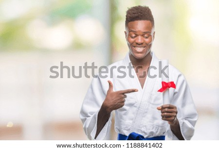 Young african american man over isolated background wearing kimono holding degree very happy pointing with hand and finger