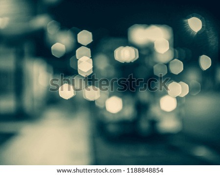 blur hexagon bokeh from cars , street lights , neon sign , and shop building in dark night after the rain , in black and white