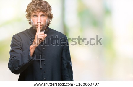 Handsome hispanic catholic priest man over isolated background asking to be quiet with finger on lips. Silence and secret concept.
