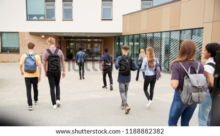 Rear View Of High School Students Walking Into College Building Together Royalty-Free Stock Photo #1188882382