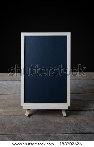 The chalkboard on the stand on Old wooden floor and black background