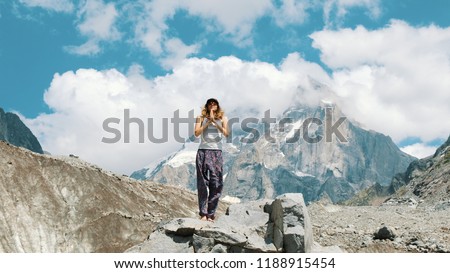 Young woman performs a basic warrior asana in yoga against the backdrop of a snowy mountain in a hike. Girl does gymnastics and gymnastics on fresh air in a hike on the nature
