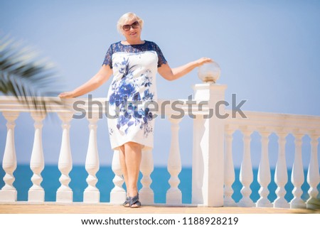 An elderly woman traveler posing, sea at the background