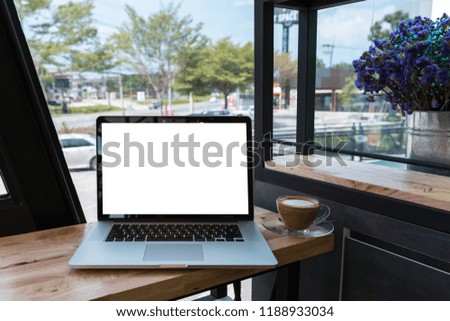 Laptop computer with coffee cup on wooden table in cafe