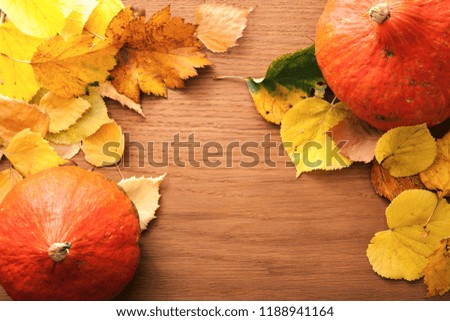 Autumn leaves and pumpkin on wooden background