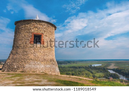 The tower of an ancient Bulgarian fortress on high cliff on the banks of the Kama River, Elabuga, Tatarstan, Russia. Ancient watchtower with blue sky on background. Trails leading to tower. Sunny day.