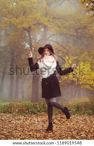 A beautiful girl in a coat and hat walks on the autumn forest
