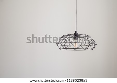 black metal chandelier hangs from the ceiling against the background of a light wall, modern style, the picture is free to write text, the vertical position