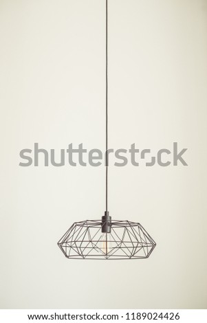 black metal chandelier hangs from the ceiling on a light wall background, modern style, the picture is free to write text, the layout is horizontal