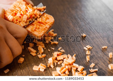 Female hands with a knife cut soap into cubes on wooden background.
