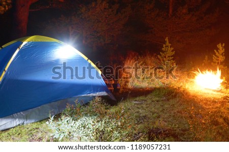 Camping at night with a tent and fire as a symbol of adventure, travel and romantic.