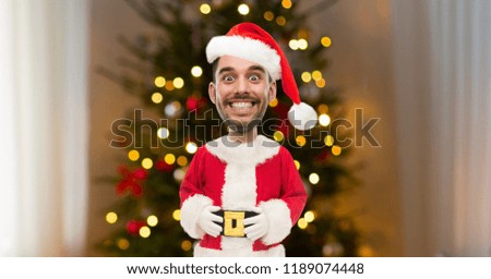 holidays, expression and people concept - smiling man with funny face in santa clothes over christmas tree lights on background (cartoon style character with big head)