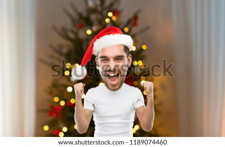 emotion, success, holidays and people concept - young man celebrating victory and screaming in santa hat over christmas tree lights on background (funny cartoon style character with big head)