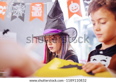 Halloween pictures. Cute good-looking brother and sister feeling busy while drawing Halloween pictures together