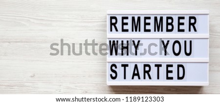 Lightbox with 'Remember why you started' words over white wooden background, overhead. Copy space.