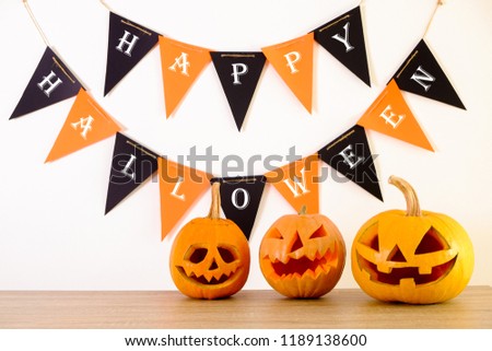 Few orange pumpkins of different size carved into Jack o Lantern on wooden table. Background, copy space, close up, top view. All hallows eve Halloween party decoration. Trick or treat concept.