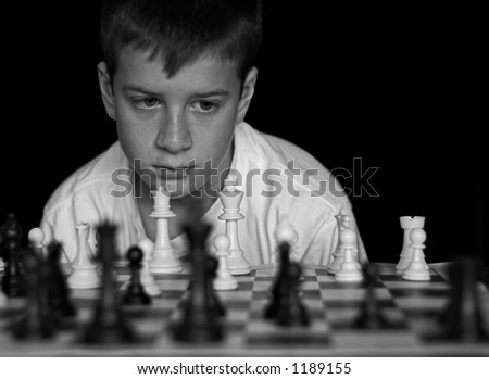 Boy playing chess on black background