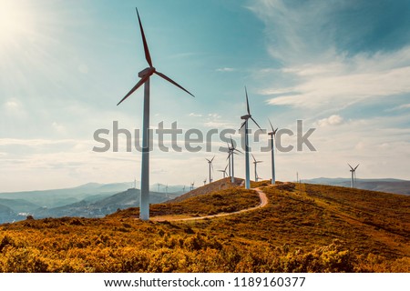 Wind turbines on beautiful sunny summer autumn mountain landsape. Curvy road through mountain Eolic park. Green ecological power energy generation. Wind farm eco field Royalty-Free Stock Photo #1189160377