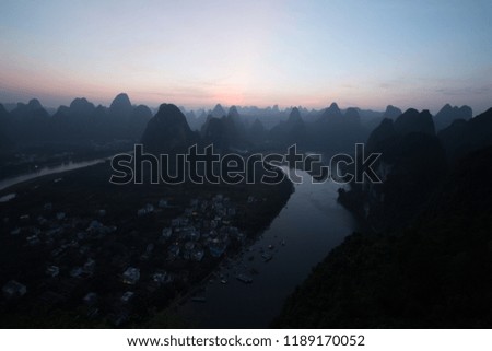 a small fisher town in asia china at dawn day sunrise and night with a lot of hills and mountains