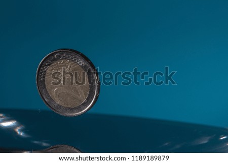 High speed macro picture of water drops and euro coins falling with a blue background