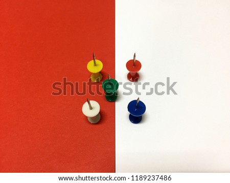 Various colored board pins on white and red background