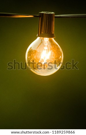 An outdoor lightbulb glowing yellow at dusk. 