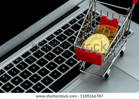Shopping carts with gold bitcoin on laptop computer isolated on black background, digital currency money trading with cryptocurrency, coin with profit, finance concept, top view.