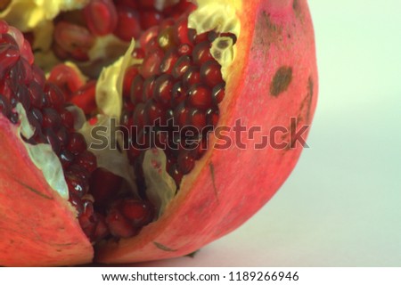 Ripe pomegranate fruit, cut and showing its own grains. Photo taken on white background, close-up. Macro photography.
