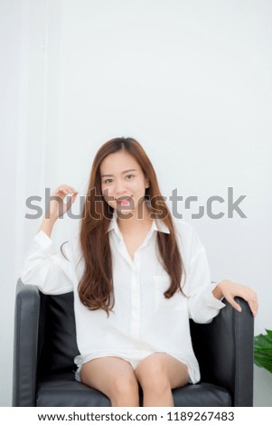 Portrait of beautiful young asian woman smile and happy sitting on chair in the living room at home, lifestyle and relax concept.