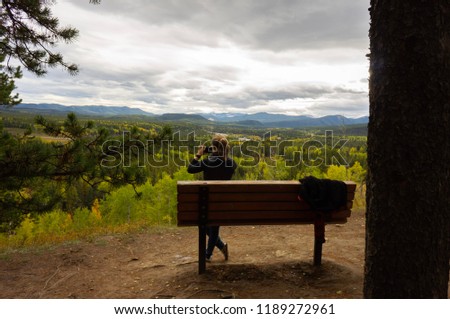 Active girl taking a picture of a the landscape with smartphone after a long hike 