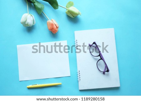 office table desk coffee notebook flower glasses and pen on blue background top view and copy space for text