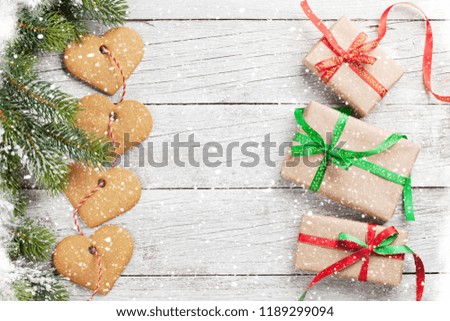 Christmas background with gift boxes, snow fir tree and gingerbread cookies on wooden table. Top view with space for your greetings