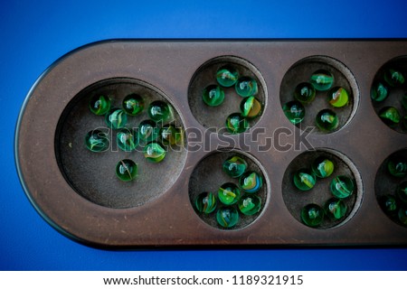 Close-up of a congkak or congklak which is a mancala marble game of Malay origin played in Malaysia, Philippines, Singapore, Indonesia, Brunei and Thailand in a blue background. Selective focus.
