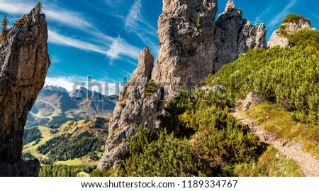 Panorama photo of the Dolomites mountains high altitude trail among group of rocks.