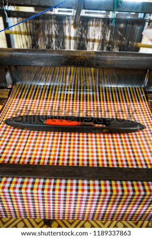 Close up of brocade fabric weaving on loom, cotton on the manual wood loom in Vietnam traditional culture. Multi-colored brocade threads on a loom. 