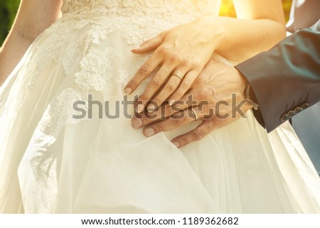 Wedding. Hands of man and woman on the white wedding dress. New family born.