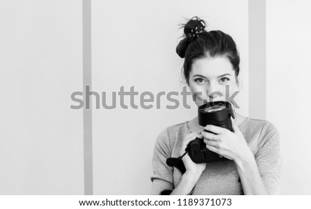 Pretty girl photographer kisses her camera and smiles, black and white photo